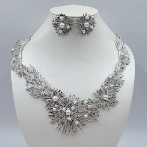 Guldhalsband och örhängen med pärlor - Elegant set med halsband och matchande örhängen i guld. Halsbandet har ett unikt designmönster med strålande detaljer och stora pärlor. Örhängena är runda med liknande strålande design och en central pärla. Perfekt för att ge en lyxig touch till din outfit. Måtten finns på bilden.