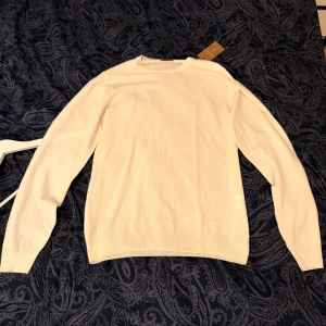 Vit krämig merinoullströja från Stenströms S - Klassisk vit krämfärgad rundhalsad tröja från Stenströms i mjuk merinoull. Långärmad och stilren modell som passar perfekt till lager-på-lager. Ribbstickade muddar vid ärmslut och nederkant ger en clean look.