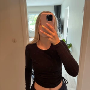 Svart ribbad långärmad topp Zara - Säljer en svart ribbad långärmad topp från Zara. Modellen är croppad med snörning i sidorna som ger en snygg passform. Mjuk och stretchig i bomullsmix, perfekt till jeans eller kjol. Enkel rund halsringning och stilren look.