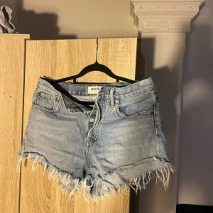 Ljusblå jeansshorts från Agolde - Snygga ljusblå jeansshorts från Agolde med råa, fransiga kanter och klassisk femficksdesign. Shortsen har hög midja och är perfekta för sommardagar. De är gjorda i mjukt denim och har en avslappnad, loose passform.