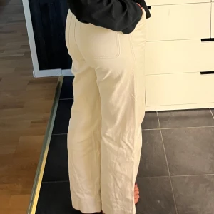 Krämvita jeans - Snygga krämvit jeans med raka ben och hög midja. Byxorna har klassiska fickor fram och bak, stängs med dragkedja och knapp. Perfekta för en clean och stilren look.