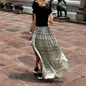 Grönvit långkjol med mönster - Flowig långkjol i grönt och vitt med unikt grafiskt mönster och elastisk midja med knyt. Kjolen har en slits på sidan som ger extra rörelse och en chill vibe. Perfekt för dig som gillar boho-stil och vill sticka ut med snygga detaljer.