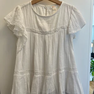 Vit blus med volangärm  - Superfin vit blus med volangärmar och rund halsringning. Blusen har tunna ränder i tyget och broderade detaljer. Väldigt bra skick, inga defekter.❣️