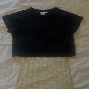 Svart croppad t-shirt från Gina  - En svart croppad t-shirt från Gina med rund hals och korta ärmar. Enkel och stilren modell i mjukt matrial, perfekt att matcha med snygga jeans. Snygg basic som funkar året runt.