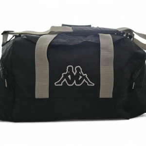 Kappa duffelväska – Svart med beige remmar -  Snygg och tålig Kappa-väska i nylon. Svart med beige remmar och broderad logga. Stort huvudfack och sidofickor. Bärhandtag + justerbar vadderad axelrem. Obs: Litet sömnadsfel bredvid en dragkedja (se bild)  Annars i närmast nyskick. Perfekt för gym, helgresor eller som kabinväska.
