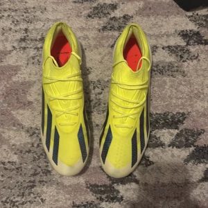 Adidas Crazyfast gula fotbollsskor - Säljer ett par Adidas Crazyfast fotbollsskor i en riktigt fräsch gul färg med blå ränder och vita detaljer. Skorna har snörning, låg profil och mönstrad sula för bästa grepp på planen. Lätta och snygga med coola röda detaljer undertill. Har använts en gång. OBS!! Utan shoe box