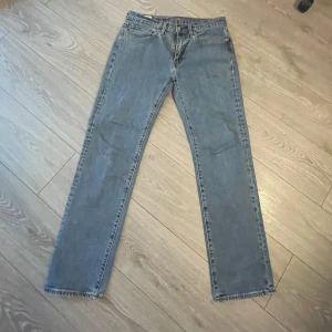 Levi's 514 raka jeans ljusblå - Klassiska Levi's 514 jeans i ljusblå denim med raka ben och normal passform. Femficksmodell med knappgylf och råa kanter nertill för en avslappnad vibe. Perfekta till sneakers eller boots.