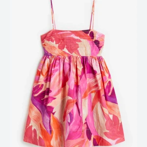 Färgglad kort sommarklänning med mönster - Superfin kort klänning med tunna axelband och färgstarkt blommigt mönster i rosa, orange, lila och beige toner. 