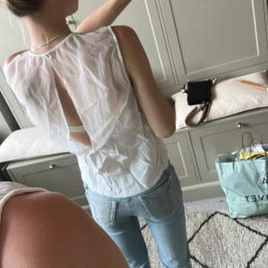 Vit ärmlös blus från Samsøe Samsøe - Säljer en superfin vit blus från Samsøe Samsøe. Toppen är ärmlös med transparent mesh upptill och en snygg öppen detalj i ryggen. Perfekt för dig som gillar stilrena och luftiga plagg med en twist. Passar till jeans eller kjol för en fräsch look.
