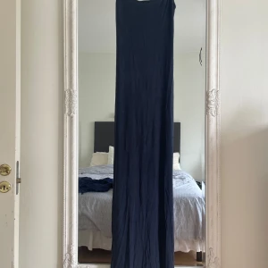 Marinblå långklänning Gina Tricot - Enkel och stilren marinblå långklänning från Gina Tricot. Klänningen är ärmlös och har en rak, slimmad passform som ger en clean look. Perfekt för dig som gillar minimalistisk stil och vill ha något bekvämt men snyggt. Har bara provat på 2 gånger