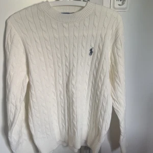 Kabelstickad Polo Ralph Lauren tröja  - Vit kabelstickad tröja från Polo Ralph Lauren. Tröjan i I jättebra skick då den endast har blivit använd 1 gång. Säljs då den är för liten. Priset kan diskuteras. Vid mer frågor, hör av er gärna 😊