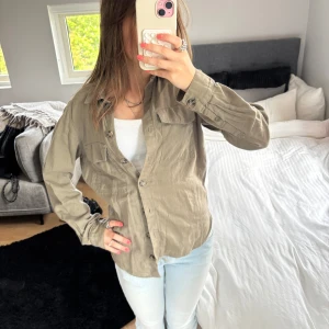 Skjorta från H&M Divided - Grön/beige skjorta från H&M Divided i storlek 32. Långärmad modell i mjuk bomull, perfekt att bära öppen eller stängd. Använd ett fåtal gånger.