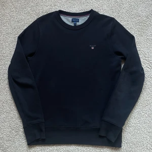 Gant sweatshirt  - Tja, säljer en tvär fet Gant sweatshirt mörkblå i storlek , tröjan är väldigt sparsamt använd och har inga defekter. Skulle säga 8/10 skick, perfekt nu till hösten då de börjar bli lite kallare, vid funderingar kom dm🥂🍾