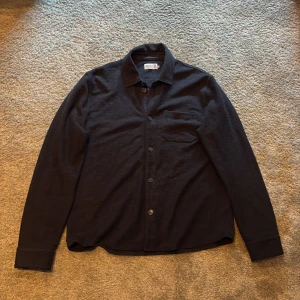 Mörkblå overshirt från Morris - Stilren svart overshirt från Morris. Perfekt att bära öppen eller stängd över en t-shirt. Storlek L men passar mig bra och jag har M. Bra skick använd några gånger. Nypris runt ca 2000.