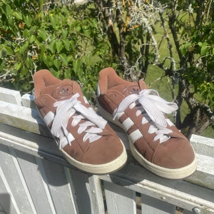 Bruna Adidas Campus sneakers mocka - Snygga bruna Adidas Campus sneakers i mocka med klassiska vita ränder och vit hälkappa. Skorna har rund tå, platt sula och vita snören. Begagnade men har inte använts i mer än ett par veckor totalt. Helt skadefria. Nypris: 2700 kr