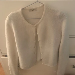 Vit kofta från Gina Tricot XS - Supermjuk och fluffig vit kofta från Gina Tricot i storlek XS. Koftan har rund halsringning, långa ärmar och knäpps med små vita knappar framtill. Perfekt för lager-på-lager och en clean look. Stl XS men passar även S