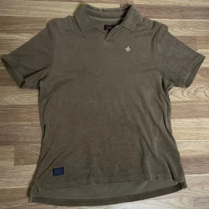 Morris frotté tröja - Snygg olivgrön t-shirt från Morris i frotté med klassisk krage och korta ärmar. Skön och avslappnad passform, perfekt för grillmiddagar och dagar på stranden. Liten broderad logga på bröstet och diskret etikett nertill. 