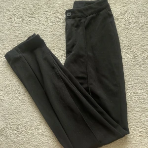 Svarta kostymbyxor  - Snygga svarta kostymbyxor med hög midja. Byxorna har en klassisk knapp och dragkedja framtill samt markerad pressveck längs benen. Perfekta för en clean och stilren look. Petite storlek oxh jag på bilden är runt 158cm lång