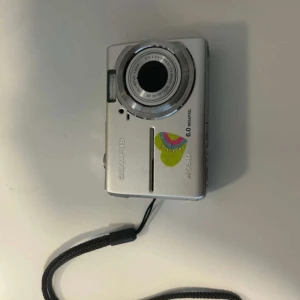 Olympus Digital kamera  - En grå Olympus kamera. Jag har ett batteri till den men ingen batteriladdare och inget minneskort. Jag fick den av min kompis och den funkade men batteriet tog slut så slutade och den sluta funka och jag har inget batteriladdare att använda så då slutar jag använda kameran. Men den kommer funka om man köper batteriladdare.💕💕