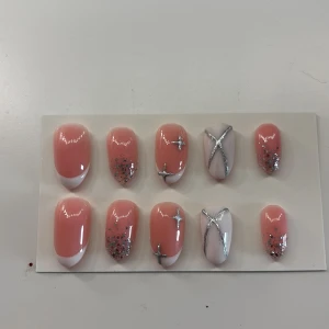 Press-on naglar rosa med glitter och silver - Handgjorda gelé Press on nails.  Snygga press-on naglar i rosa med fransk tipp, silverglitter och silvriga stjärndekorationer. Några naglar har vit bas med silvriga linjer. Inkluderar tillbehör som nagelfil, träpinne och rengöringsduk. Perfekt för dig som vill ha en trendig och glammig look. Man får även med instruktion på hur man sätter på de❤️och klisterlappar.