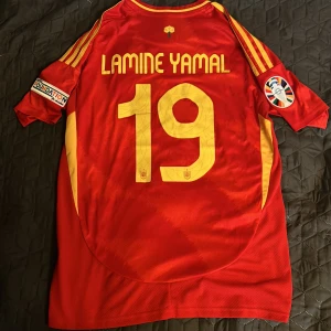 Lamine Yamal Fotbollströja Spanien EM 2024 - Säljer en Spanien EM 2024 Fotbollströja i Storlek M med Lamine Yamal 19 på ryggen, inkluderar även EM märket på höger armen 