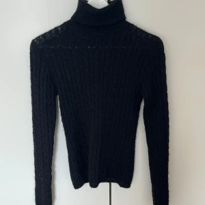 Svart ribbad polotröja från BikBok - Säljer en svart ribbad polotröja från BikBok i storlek XS. Tröjan är stickad med lång ärm och har en hög polokrage. Perfekt för lager-på-lager under kyligare dagar.