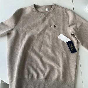 Beige sweatshirt från Polo Ralph Lauren - Säljer en beige sweatshirt från Polo Ralph Lauren. Tröjan är inte använd något. Den är i storlek S. 
