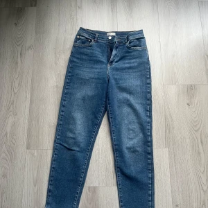 Blå jeans från gina tricot perfect jeans - Säljer ett par klassiska blå jeans från gina tricot perfect jeans i storlek 40. Jeansen har fyra fickor, knapp och dragkedja framtill samt raka ben. Säljs i mycket bra skick, använd 1 gång.