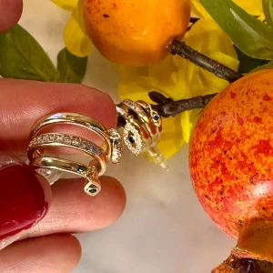 Örhängen  med ögonberlocker - Örhängen med glittrande stenar och hängande ögonberlocker i blått och vitt. Örhängen har en modern design med flera band och detaljer som ger en unik look.