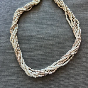 Pärlhalsband i flera rader - Säljer ett snyggt halsband med flera rader av små, oregelbundna pärlor i en skimrande vit och silveraktig nyans. Halsbandet har en tvinnad design som ger en cool och unik look. Perfekt för att lyfta vilken outfit som helst!
