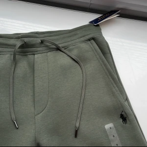 Gröna mjukis shorts från Polo Ralph Lauren - Snygga gröna mjukis shorts från Polo Ralph Lauren med dragsko i midjan och klassisk broderad logga på benet. Shortsen har sidofickor och är perfekta för en avslappnad stil. Passar M