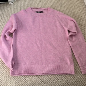 Ljusrosa stickad tröja från Vero Moda - Mysig ljusrosa stickad tröja från Vero Moda. Tröjan har rund halsringning, långa ärmar och ribbade muddar vid ärmslut och nederkant. Perfekt för lager-på-lager under kyliga dagar. Aldrig använt.