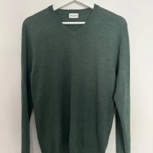 Grön v-ringad tröja från John Henric - Mörkgrön v-ringad tröja från John Henric. Klassisk modell med lång ärm och ribbade muddar vid ärmslut och nederkant. Perfekt för lager-på-lager och enkel att matcha med olika outfits.