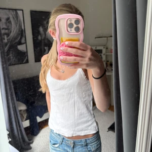 Vit ribbad linnetopp - Säljer en enkel och fräsch vit ribbad linnetopp med smala axelband. Perfekt till jeans eller kjol för en avslappnad look. Toppen har en lätt v-ringning och är i ett mjukt material.