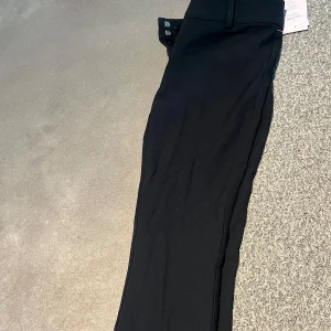 Svarta kostymbyxor  - Snygga svarta kostymbyxor från Nelly med klassisk passform och raka ben. Byxorna har hällor för bälte och stängs med dold dragkedja och knapp framtill. Perfekta för en stilren look. Säljer pga av att det var för liten storlek. Skicka gärna till mig vid vidare frågor😊🫶🩷