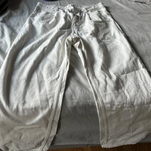 Vita wide jeans från Lee - Säljer ett par vita jeans från Lee med bred passform och raka ben. Klassisk femficksmodell med dragkedja och knapp framtill. Perfekta för en avslappnad och trendig stil.