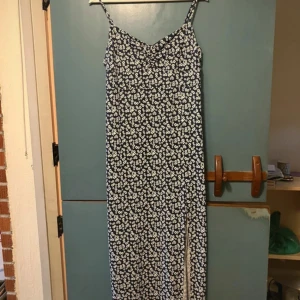 Blommig långklänning från Gina Tricot - Säljer en marinblå långklänning med vita blommor från Gina Tricot. Klänningen har smala axelband, slits på sidan och en lätt rynkad detalj vid bysten. Perfekt för varma dagar och somriga tillfällen. Står XL, men passar mig som brukar ha mellan M/L.