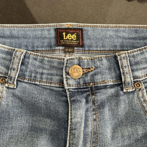 Blå jeans från Lee - Säljer ett par klassiska blå jeans från Lee med rak passform och normal midja. Jeansen har fem fickor och Lee-logga på bakfickan. Perfekta till vardags och lätta att matcha med olika stilar. Storlek 31W L32