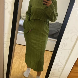 Grön ribbad långklänning - Säljer en grön långklänning med ribbad struktur och lång ärm. Klänningen har en avslappnad passform och är perfekt för dig som gillar en stilren look med lite extra textur. Passar både till vardags och när du vill känna dig extra bekväm.