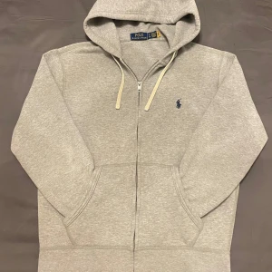 Polo Ralph Lauren Zip Hoddie - Köpt för bara en månad sen! Superfräsch och i toppskick. Storlek S men passar XS.  Färgen är stilren grå, går med allt🔥 Mjukt och skönt material, perfekt inför hösten  (Inga fläckar eller nopprig) Ordinarie pris: 2300kr