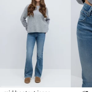 Blå bootcut jeans med hög midja - Säljer ett par klassiska blå bootcut jeans med medel låg midja och två knappar framtill. Jeansen har en lätt tvättad look och raka bakfickor med dekorativa sömmar. Perfekta till vardags med en stickad tröja eller t-shirt.
