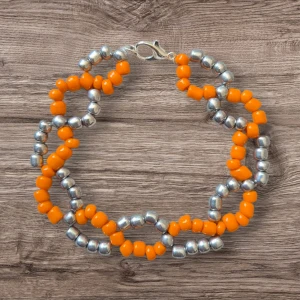 Handgjort armband - Orange & Silver Pärlarmband – Färgstarkt och Unikt  Ge din outfit en färgglad touch med detta handgjorda armband i en vacker tvistdesign. Klara orangea pärlor slingrar sig tillsammans med glansiga silverpärlor och skapar ett unikt och modernt utseende. Armbandet är avslutat med ett silverfärgat klolås för en säker och stilren stängning – perfekt för dig som vill sticka ut med dina accessoarer.  Handgjort med omsorg och noggrannhet
