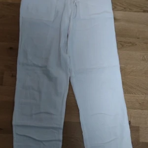 Vita linnebyxor - Säljer ett par vita linnebyxor med rak passform. Byxorna har en enkel och stilren design, perfekta för varma dagar. Lätta och luftiga med klassisk midja och utan synliga detaljer. Säljer pga det är för korta på mig
