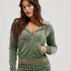 Grön juicy kofta -  Grön juicy kofta i jätte bra skick. Säljer en mjuk och skön grön hoodie i velour med dragkedja framtill och huva. Tröjan har långa ärmar, ribbade muddar och fickor på magen. Perfekt för en avslappnad stil eller myskväll hemma.