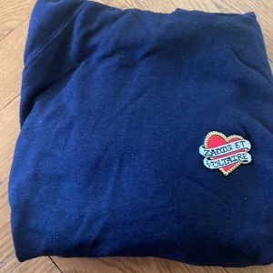 Mörkblå hoodie från Zadig & Voltaire - Säljer en snygg mörkblå hoodie från Zadig & Voltaire med en cool hjärtapplikation på bröstet. Hoodien har en praktisk magficka och justerbara snören i huvan. Perfekt för en avslappnad stil!