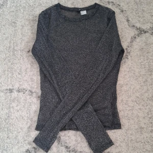 Svart glittrig långärmad topp -  Svart glittrig topp med långa ärmar. Materialet är genomskinligt. Tyget är stretchig. Skulle säga att den passar xs och s. Tröjan andvänd 1gång. 