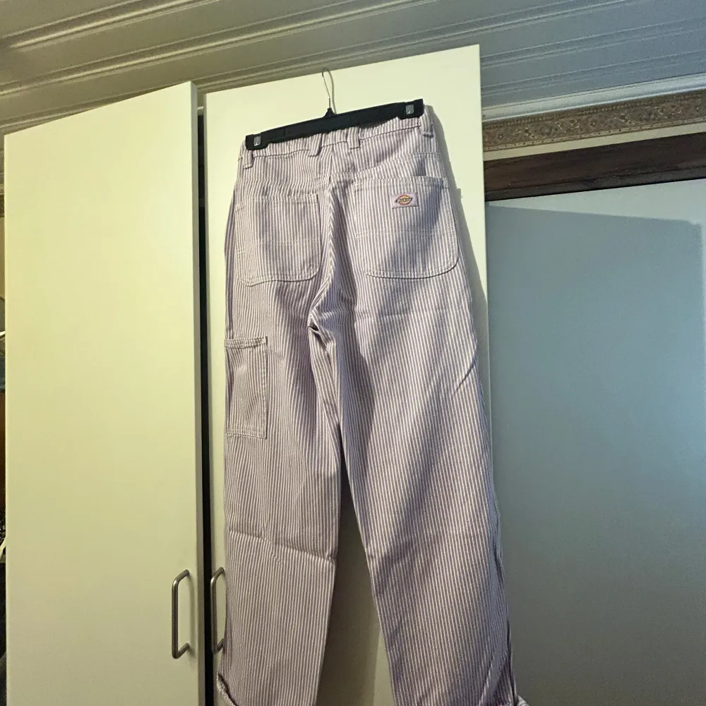 Säljer ett par vita och lila randiga byxor från Dickies med raka ben och normal passform med skickar stil. Byxorna har fickor både fram och bak samt klassisk Dickies-logga på bakfickan. . Farkut & Housut.