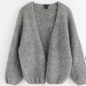 Grå stickad kofta - Lindex - Mysig grå stickad kofta med oversized passform och långa ärmar. Koftan har en djup v-ringning och är perfekt att slänga på sig över en topp. Enkel och stilren design utan knappar eller dragkedja. 