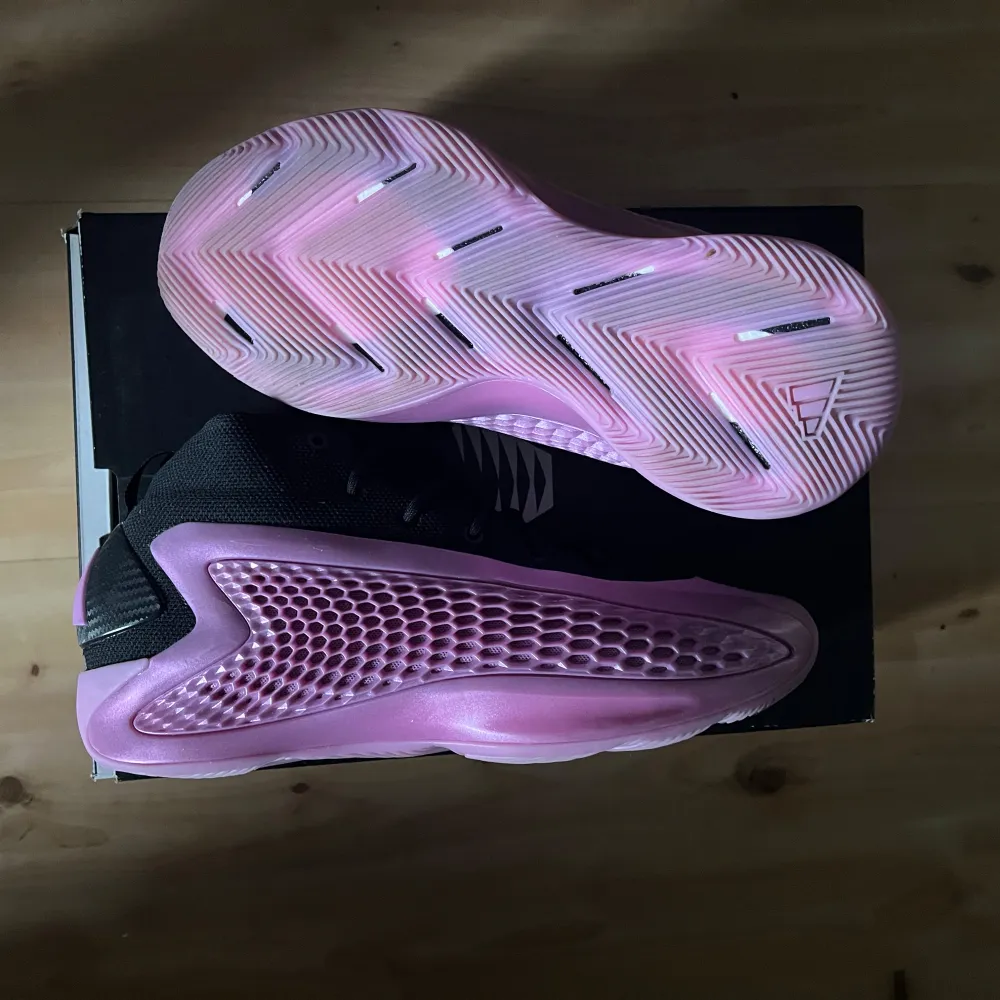 Säljer ett par unika sneakers från Adidas med svart ovandel och en iögonfallande lila sula med bikakemönster. Skorna har snörning och en sportig vibe.. Kengät.