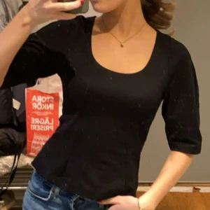 Svart topp med trekvartsärm - Snygg svart topp med trekvartsärm och rund halsringning. Perfekt för en stilren look. Helt ny. 